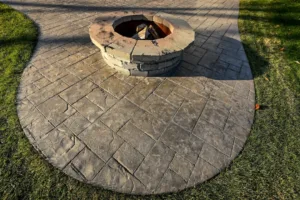 round stone fire pit on stamped concrete patio in grass yard